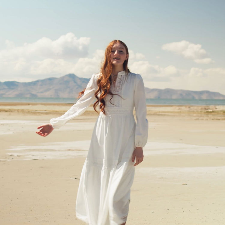young woman in a white dress standing in the desert