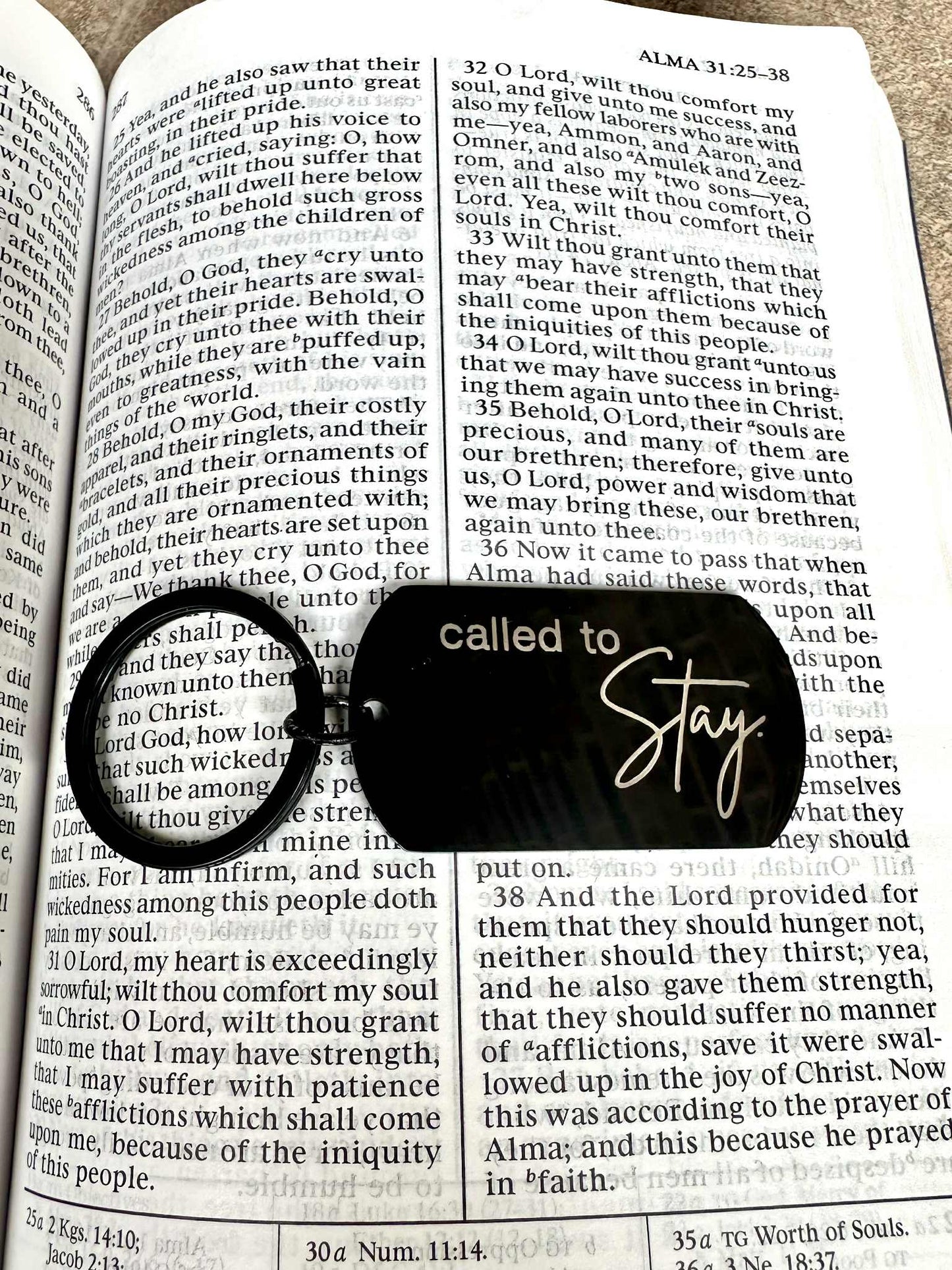 Black keychain with 'called to Stay' on a book page