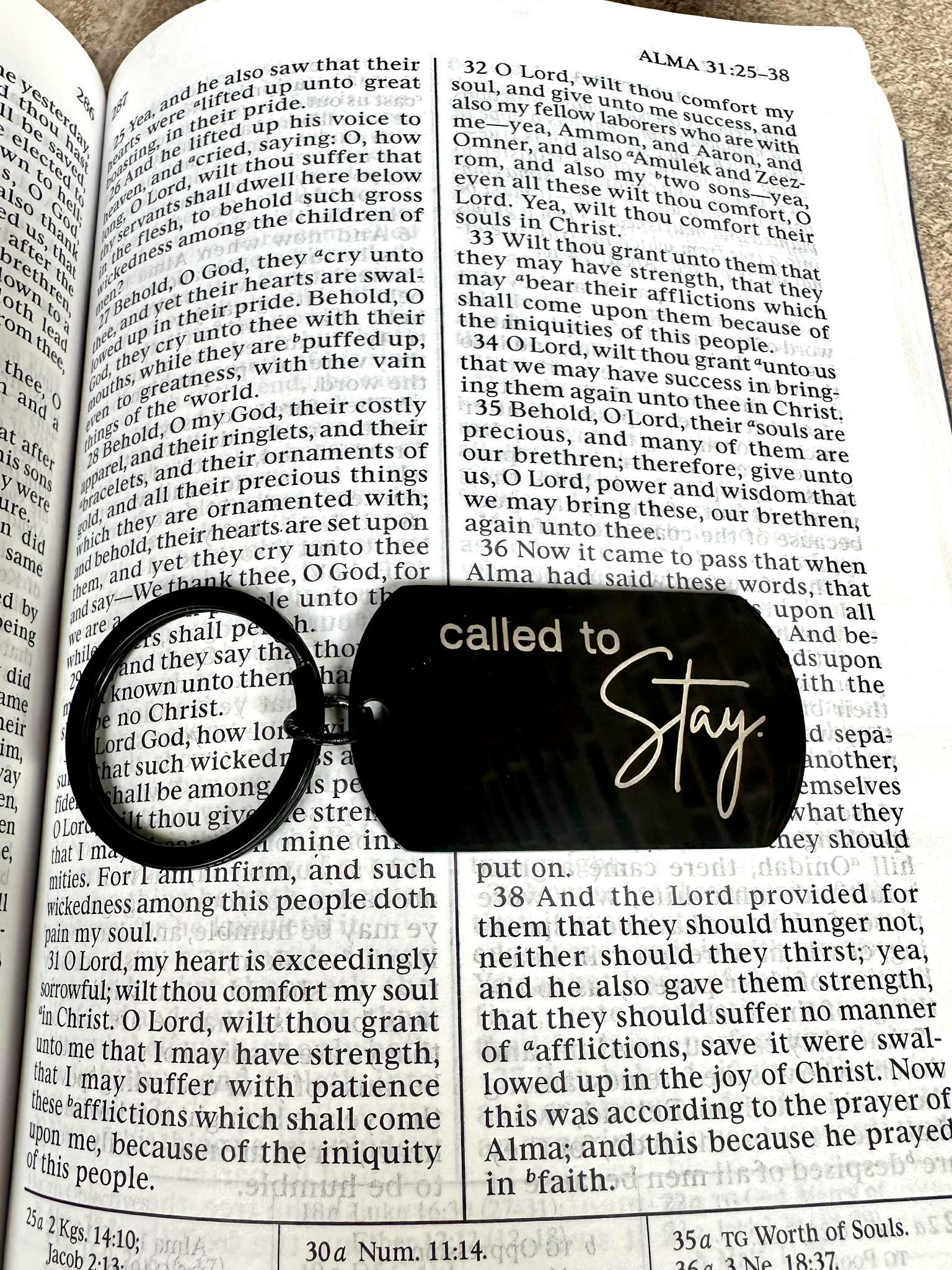 Black keychain with 'called to Stay' on a book page