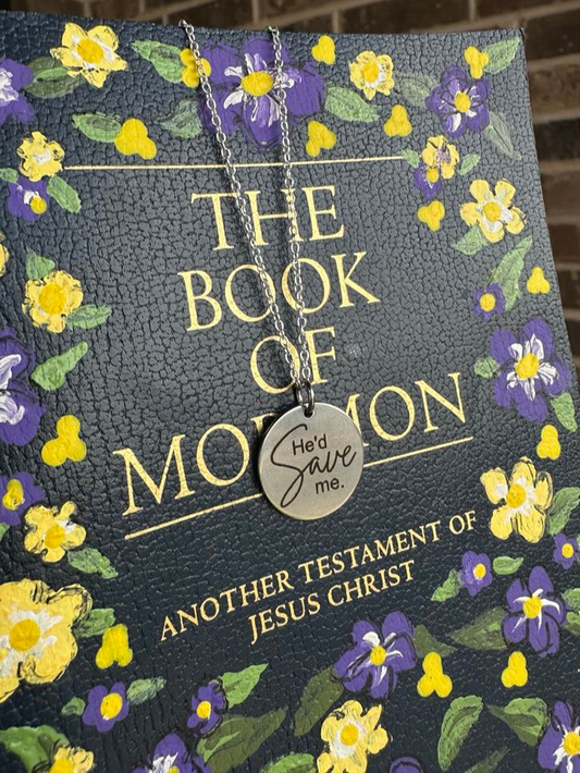 Book of Mormon with floral design and a silver He'd Save Me necklace on top.