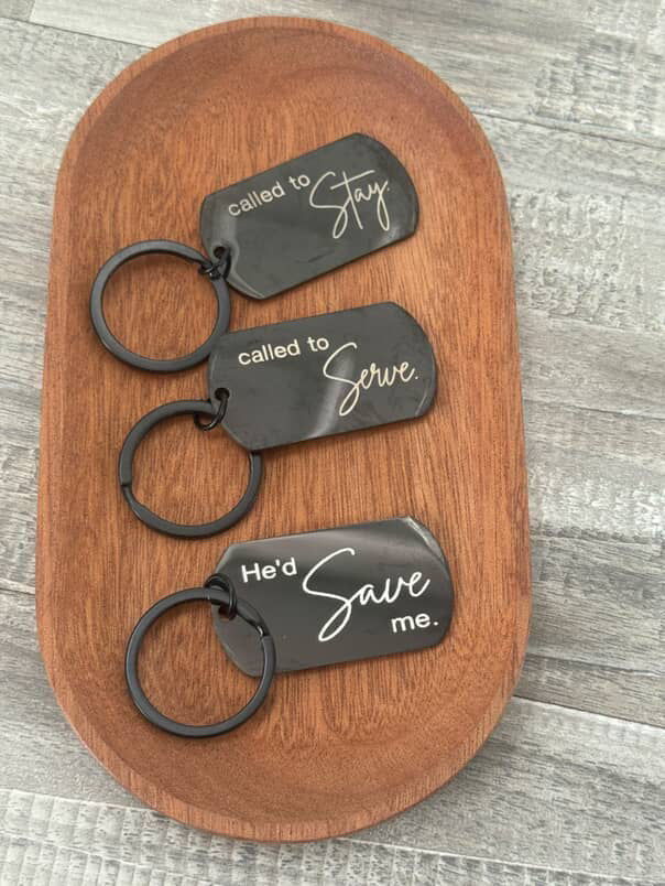 Three keychains with engraved text on a wooden surface