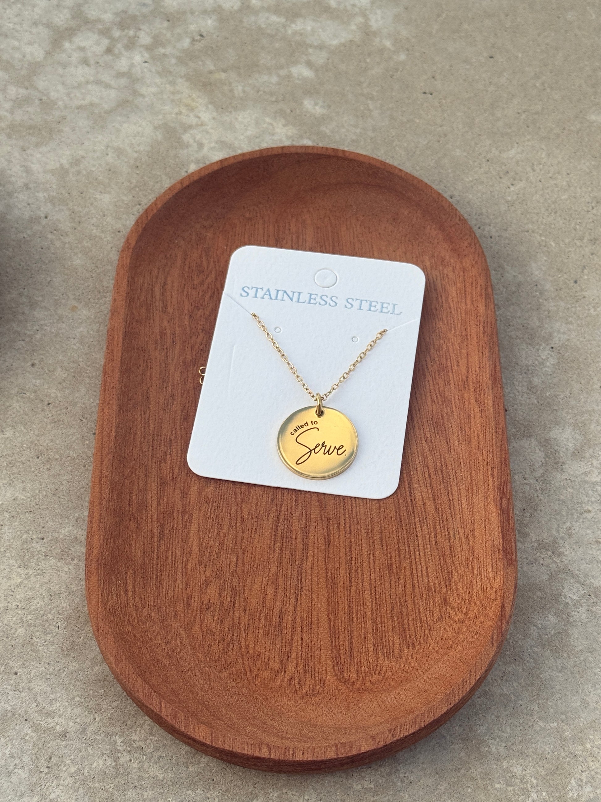Gold necklace with a pendant on a wooden tray