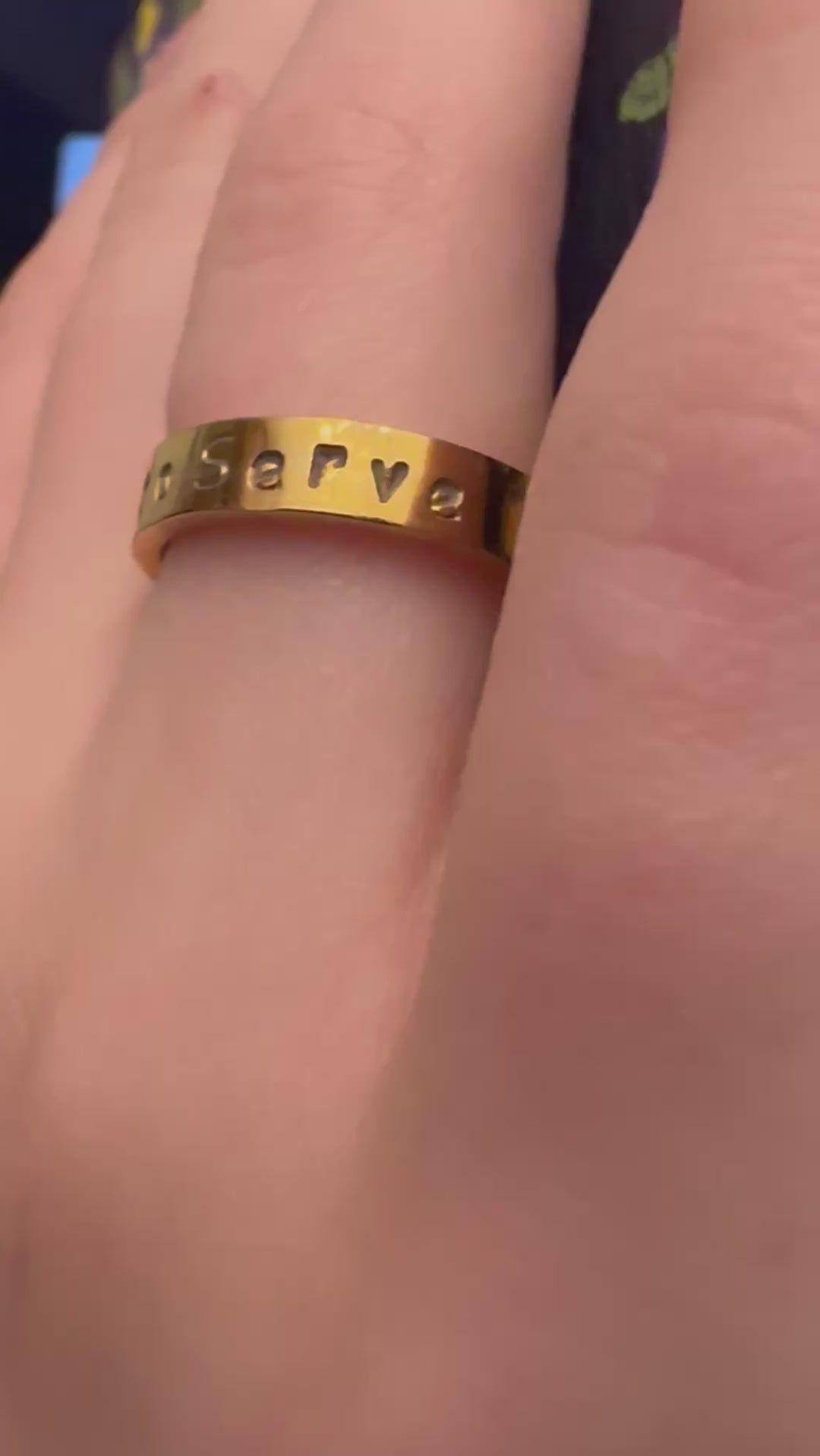 gold ring that says called to serve on a finger
