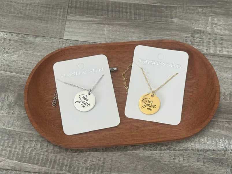 Two necklaces on display cards with engraved text on a wooden tray.