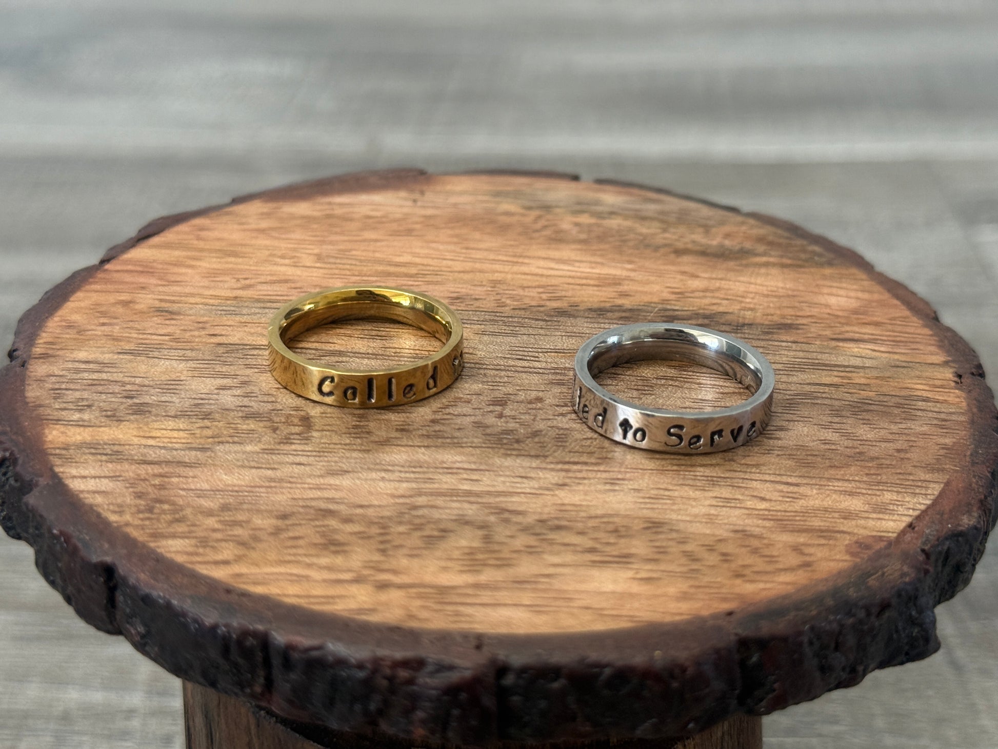 Two rings, one gold and one silver, on a wooden surface.