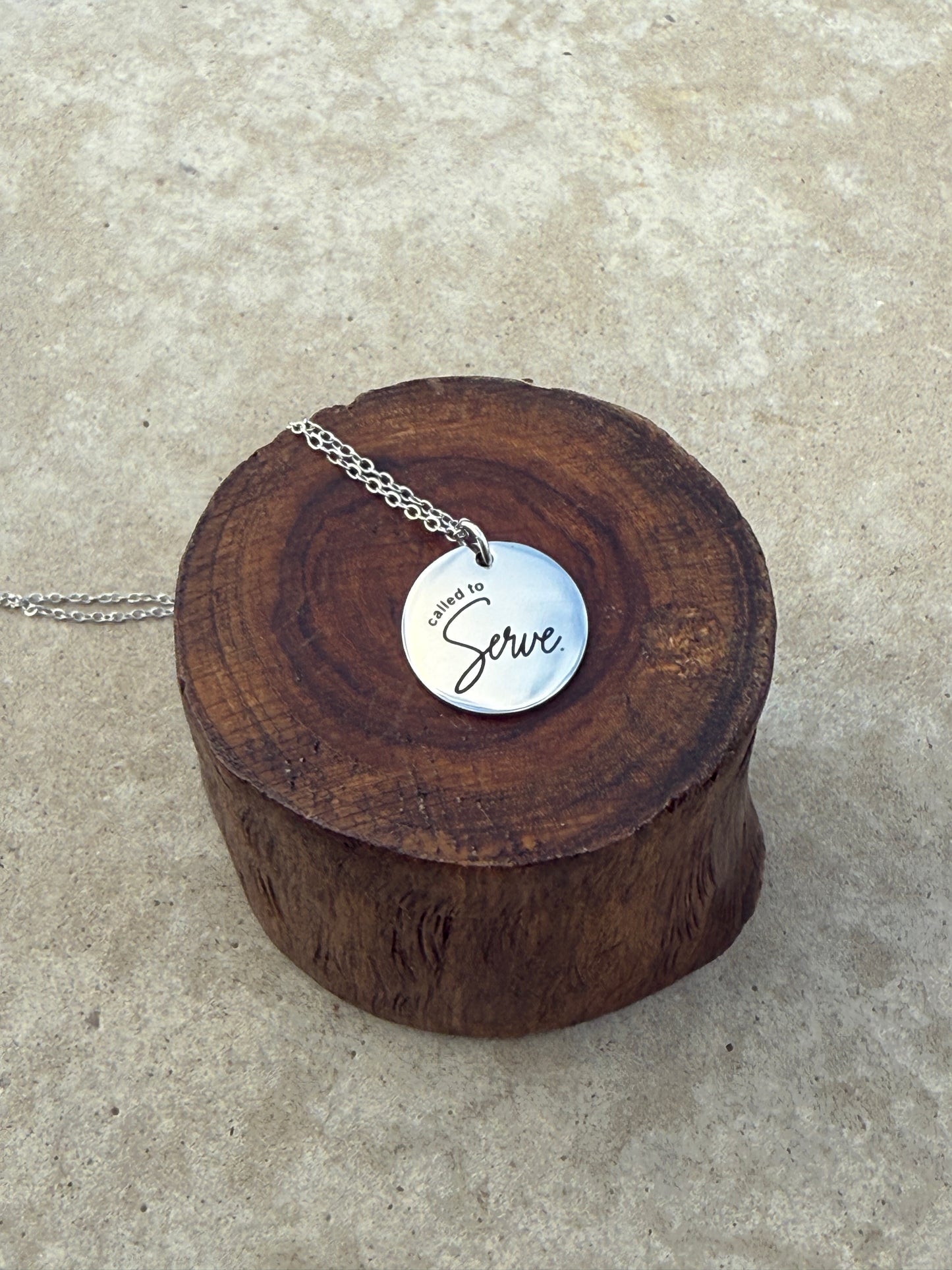 Silver necklace on a wooden stand with a brand label on a concrete surface