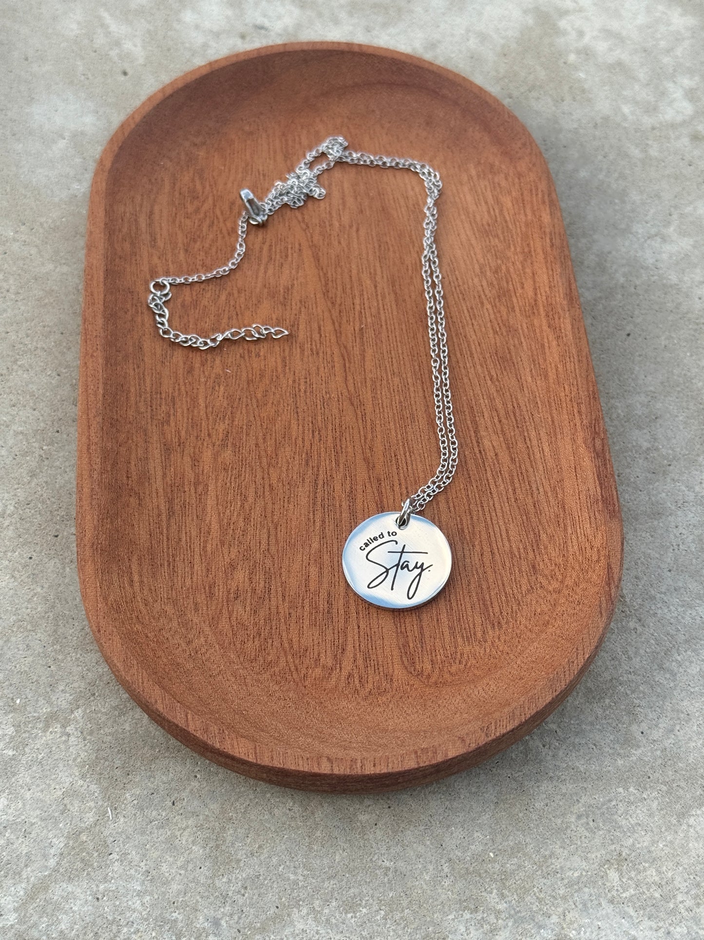Silver necklace with a round pendant on a wooden surface
