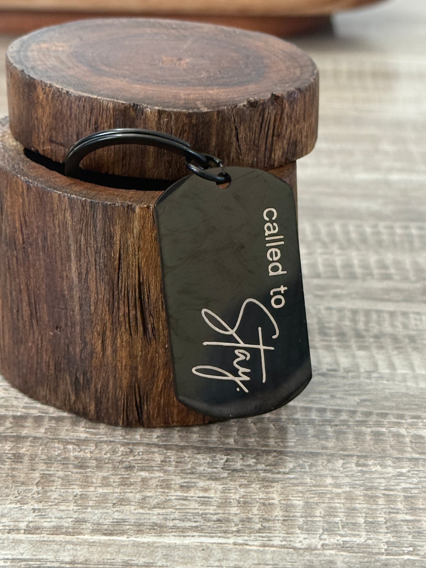 Black keychain with 'called to stay' text on a wooden block